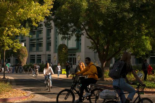 image of a UC Davis student on bike in front of library