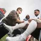 sports trainer looks at football player's leg