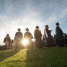 sun sets while graduates stand in a line at graduation